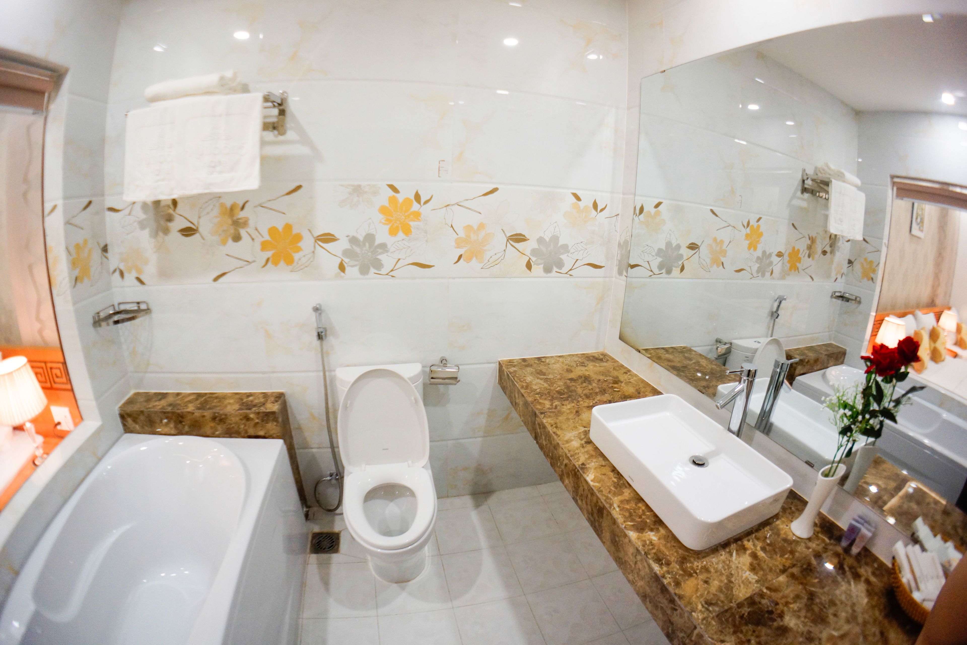 Un baño con bañera, inodoro, lavabo y un espejo grande.