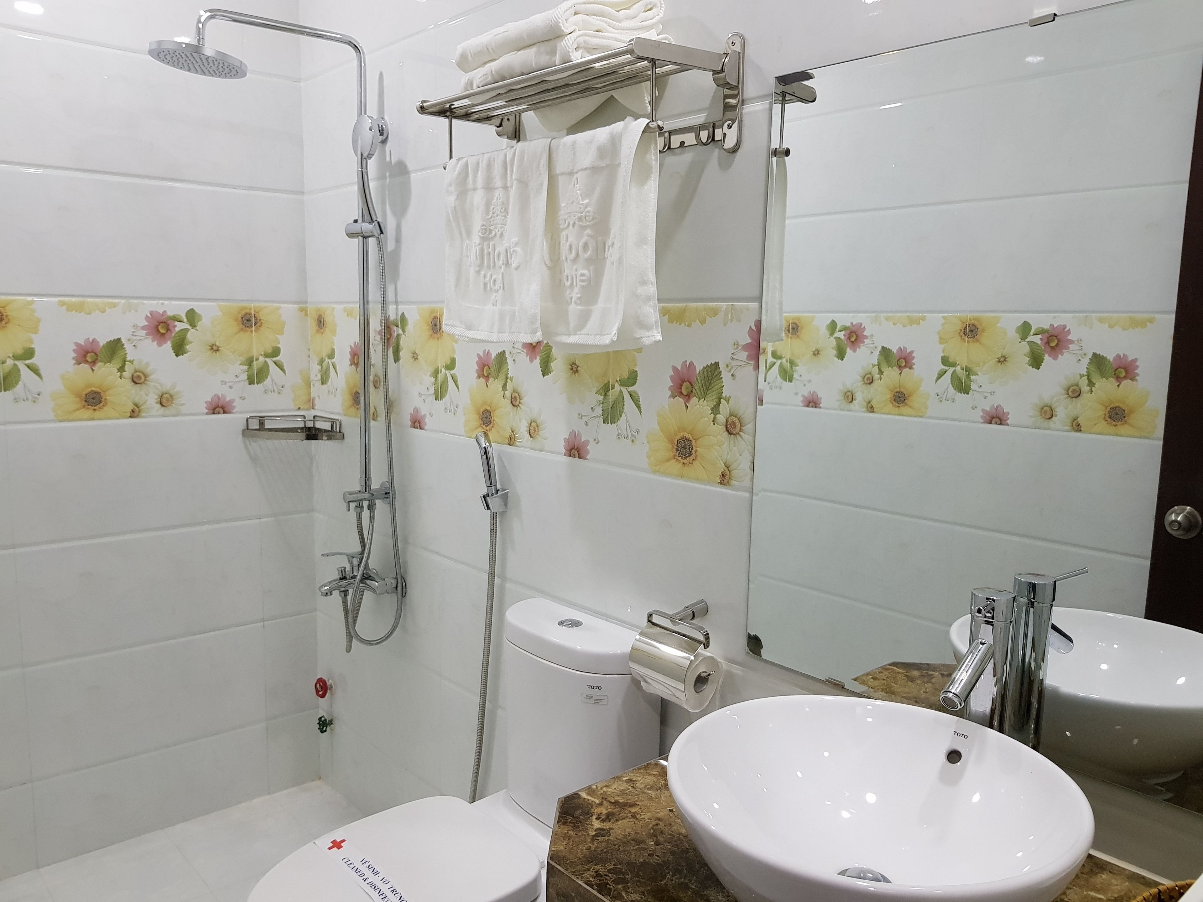 A bathroom with a toilet, two sinks, a shower, and a towel rack.