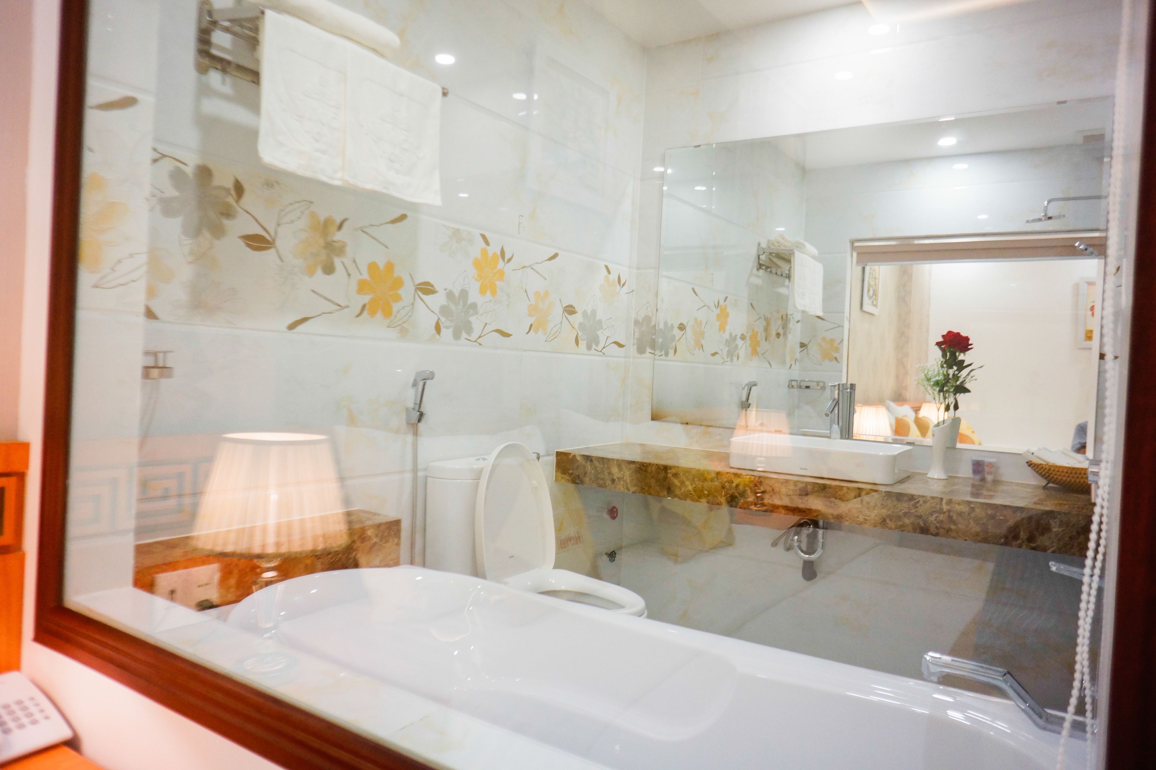 A modern bathroom with a glass shower enclosure, a white bathtub, a marble countertop, and a large mirror.