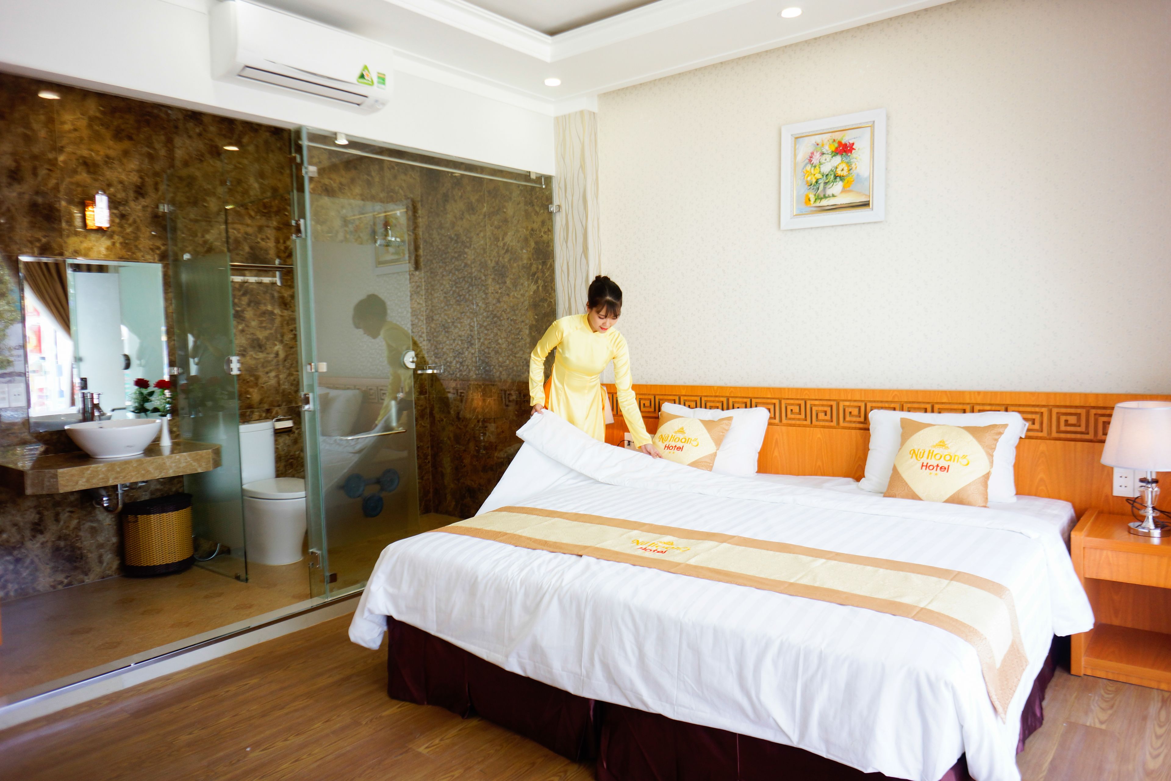 Habitación de hotel con una cama grande, un baño con cabina de ducha de vidrio y un cabecero de madera.