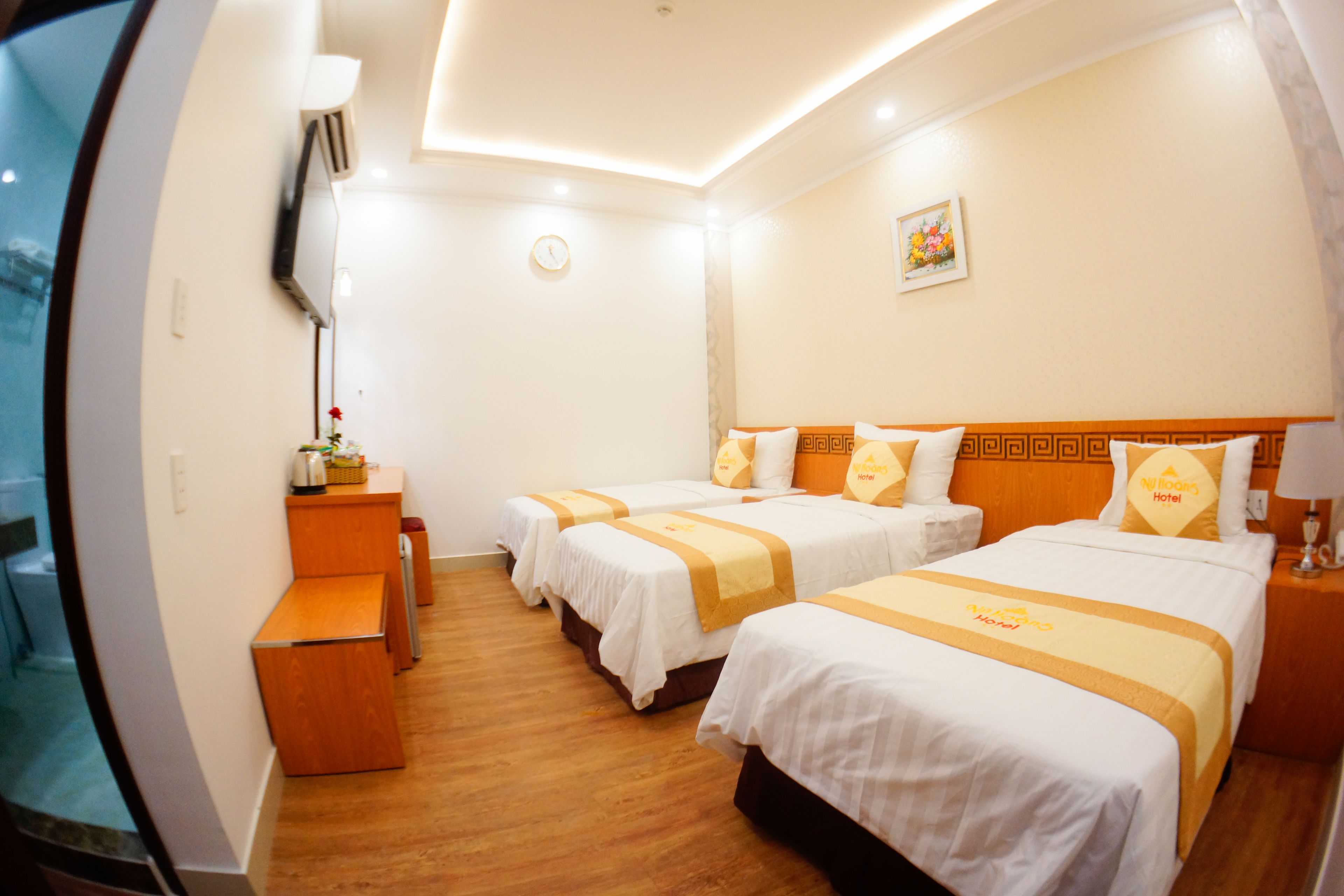 Une chambre d’hôtel avec deux lits, un bureau, une chaise, une télévision et une petite table avec une lampe.