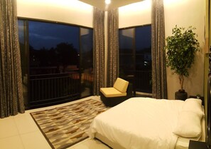 A bedroom with a large bed, a chair, a potted plant, and a view of the outside. - Atlantis Pool Villa Ipoh (Ipoh)