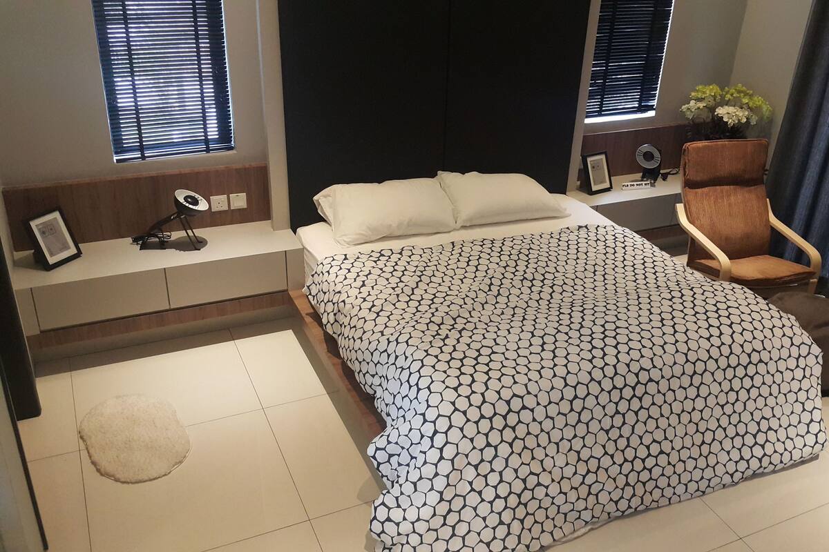 Quarto moderno com uma cama, uma cadeira, uma escrivaninha e uma janela com persianas.