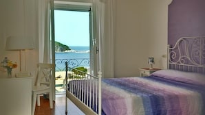 Un dormitorio con cama, escritorio, silla, ventilador de techo y vista al mar.