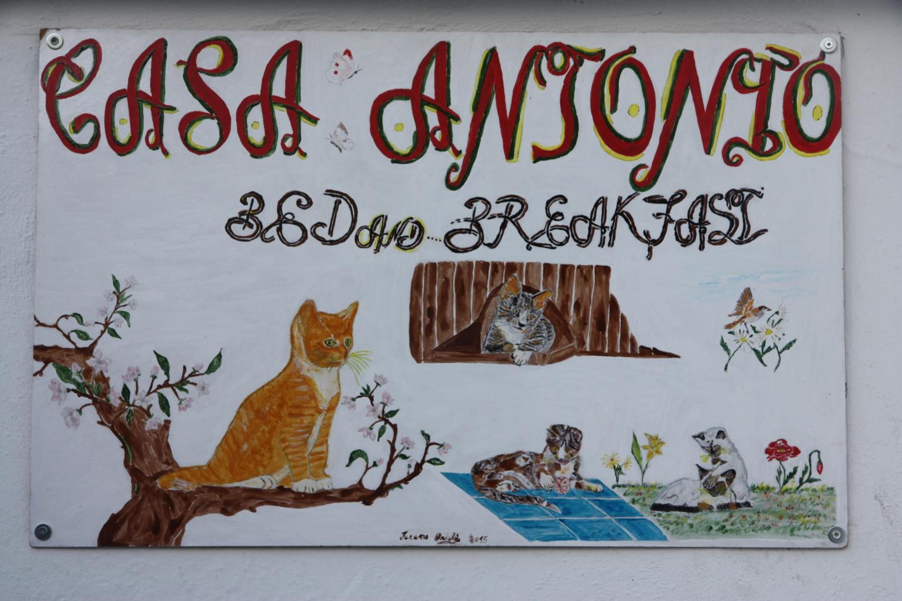 A sign with 'Casa Antonio' and 'Breakfast' written on it, featuring illustrations of cats and flowers.