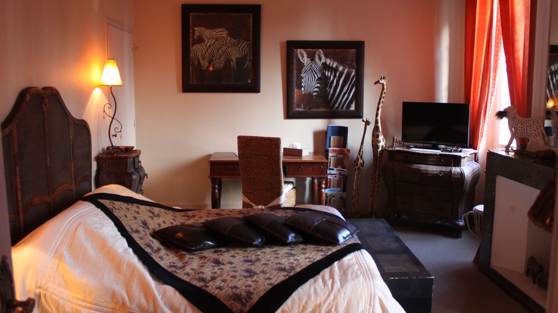 Un dormitorio con cama, escritorio, televisor y dos cuadros en la pared.