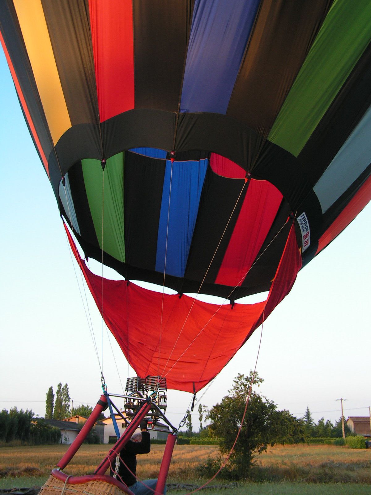 Un globo aerostático con una cubierta colorida, amarrado a una estructura de soporte en el suelo.