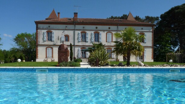 Un edificio grande de dos pisos con una piscina al frente.