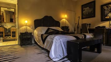 A bedroom with a large bed, two bedside tables, a bench, a dresser, a mirror, and wall art.