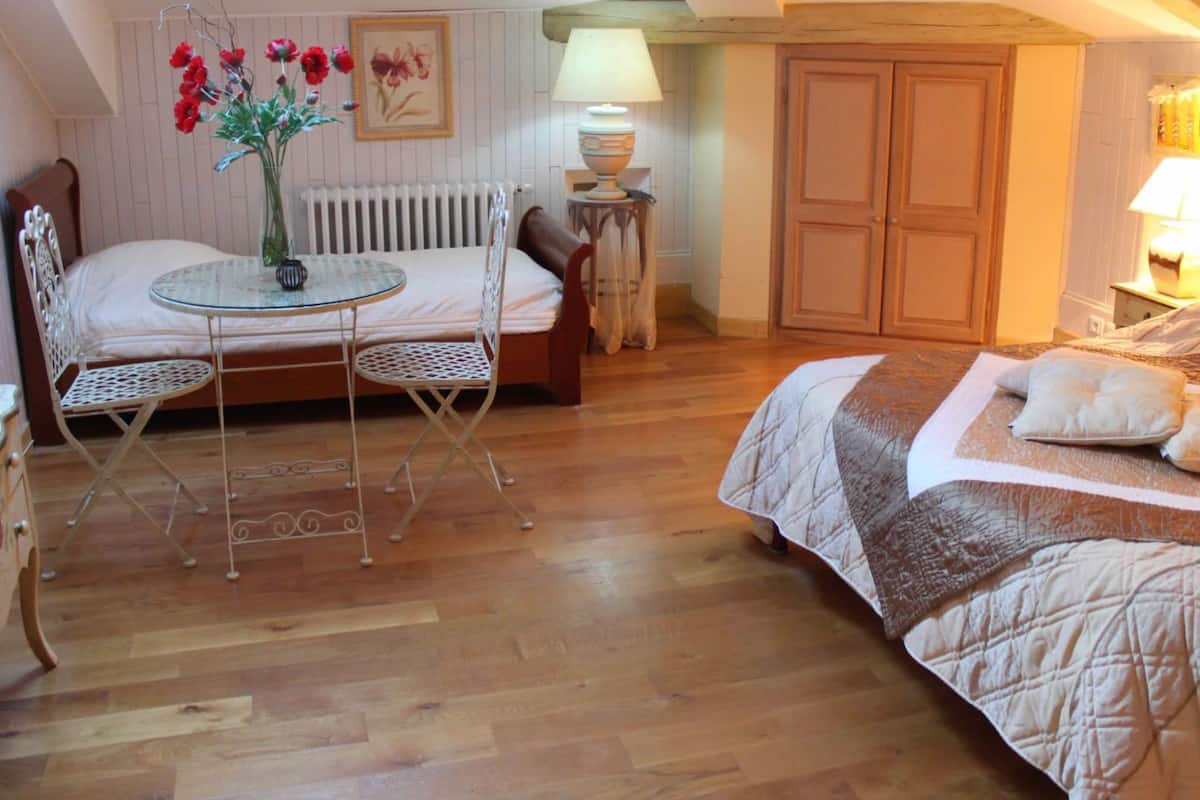 Een knus slaapkamer met een bed, een tafeltje met stoelen, een radiator en een lamp.