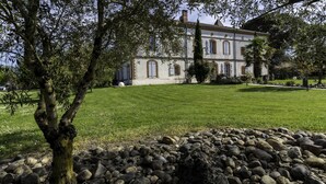Un edificio grande de dos pisos con un césped bien cuidado y un muro de piedra al frente.