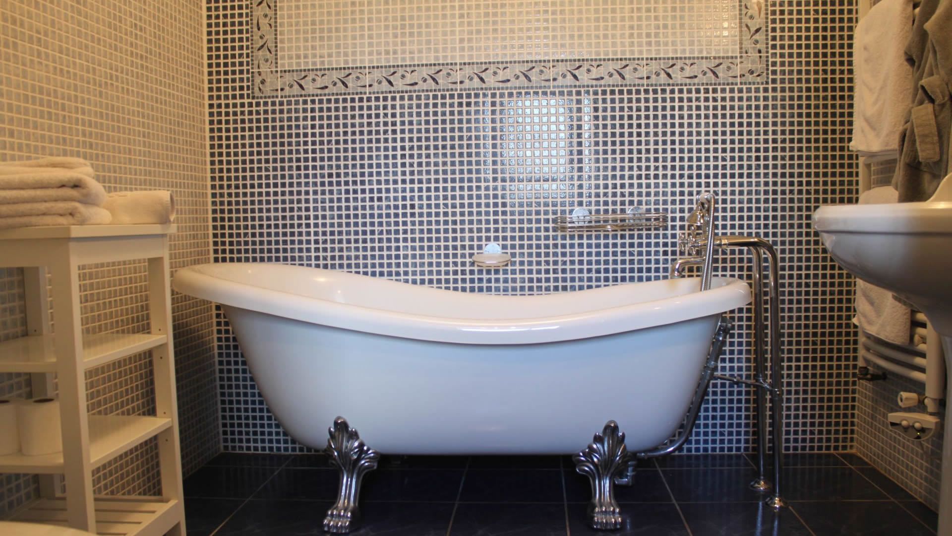 Ein Badezimmer mit einer freistehenden Badewanne, einem weißen Ablagefach mit Handtüchern und einem Waschbecken mit Handtuchhalter.