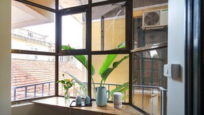 Janela com vista para prédios e um vaso de planta.