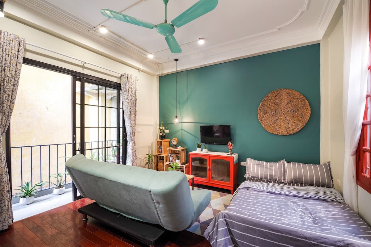 A room with a sofa, a bed, a TV, and a ceiling fan.