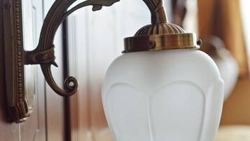 A wall-mounted light fixture with a white shade and a brass bracket.