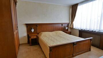 A bedroom with a wooden bed, nightstands, a dresser, and a radiator.