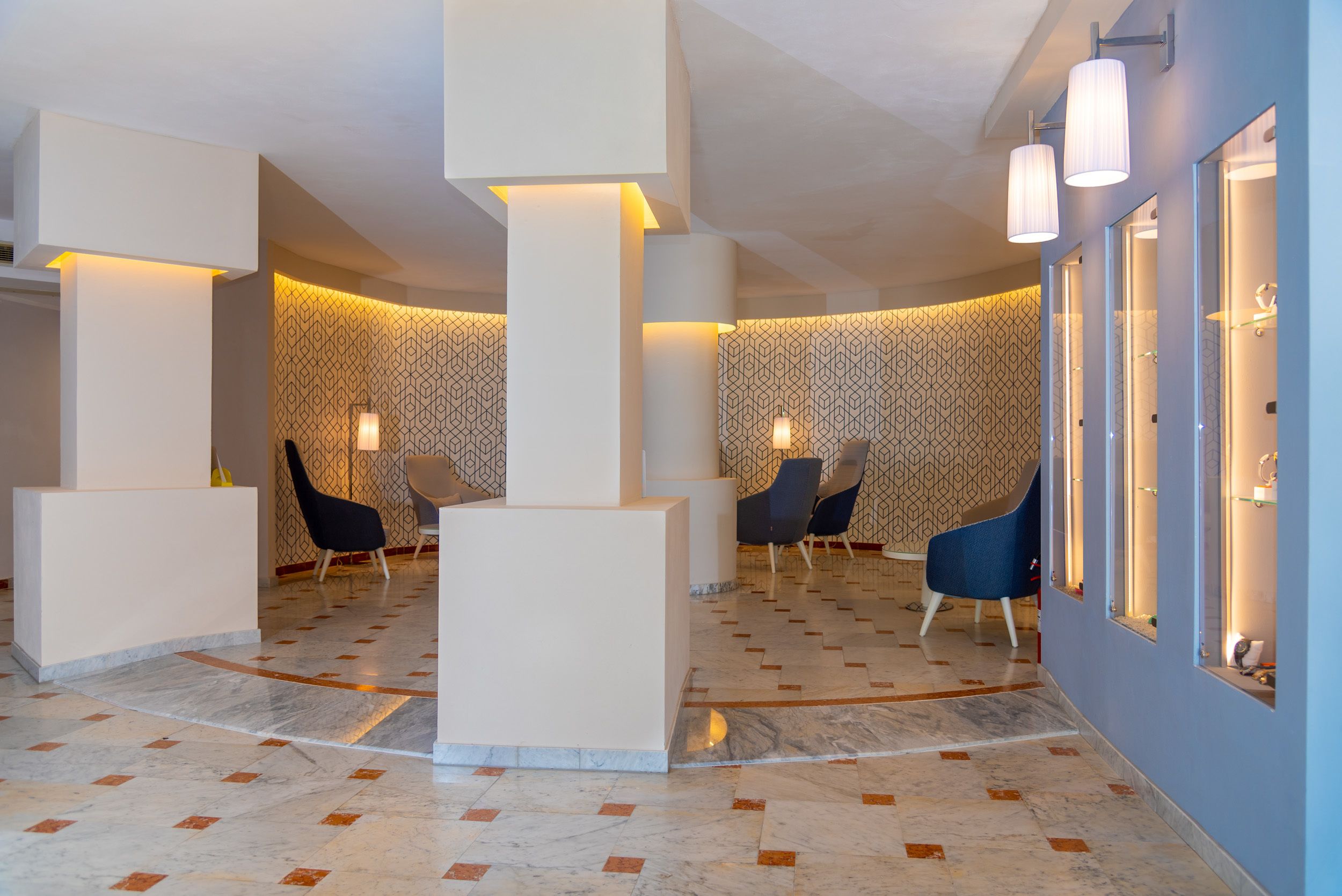A modern lobby with a marble floor, geometric patterned wallpaper, and contemporary seating.