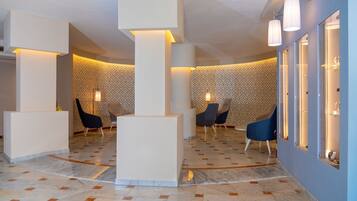 A modern lobby with a marble floor, geometric patterned wallpaper, and contemporary seating.