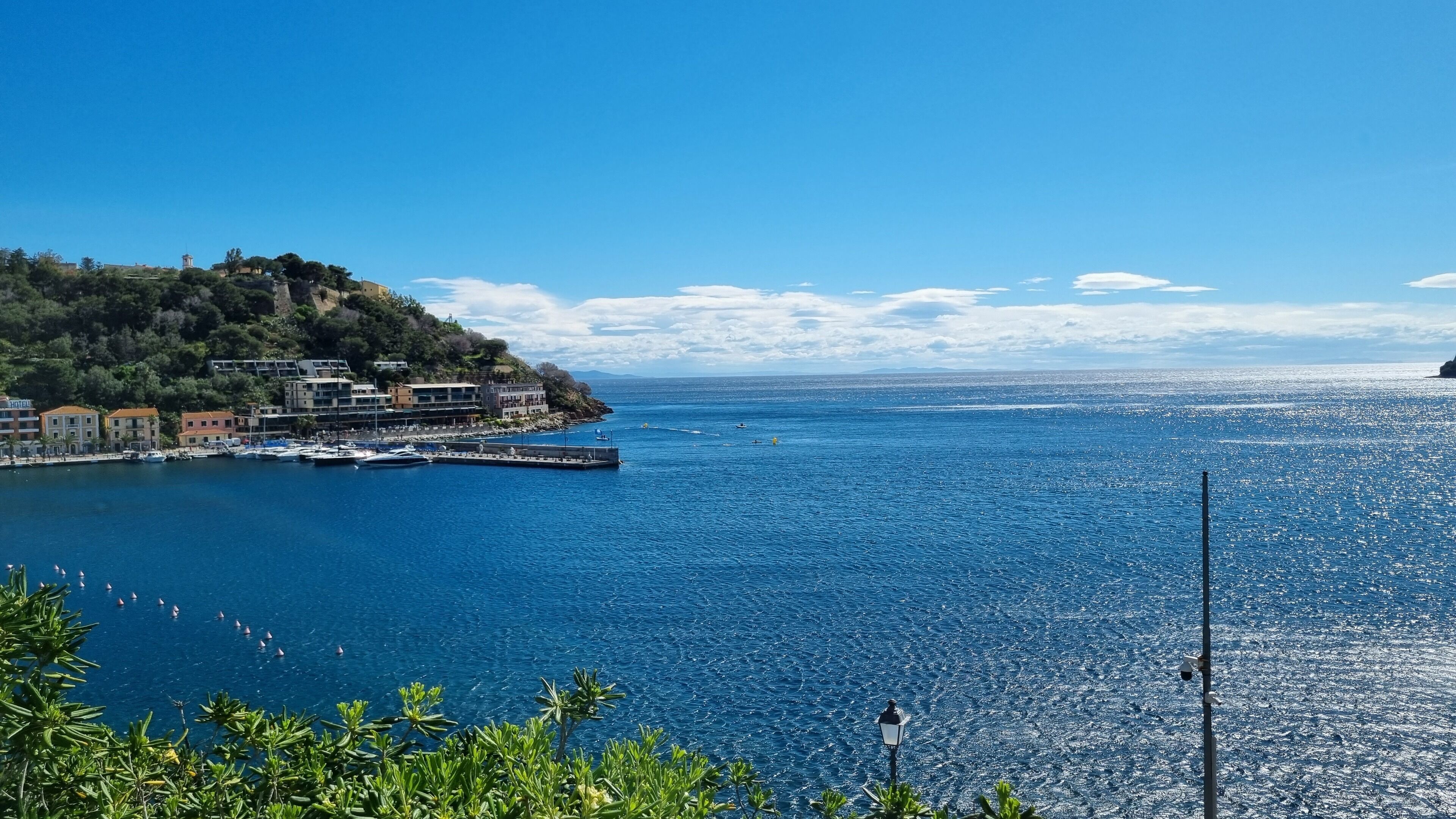 A coastal town with a marina, buildings, and a clear blue sea.