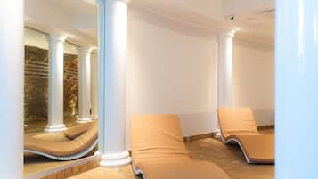 Une salle de spa avec deux fauteuils inclinables, des colonnes blanches et un sol en pierre.
