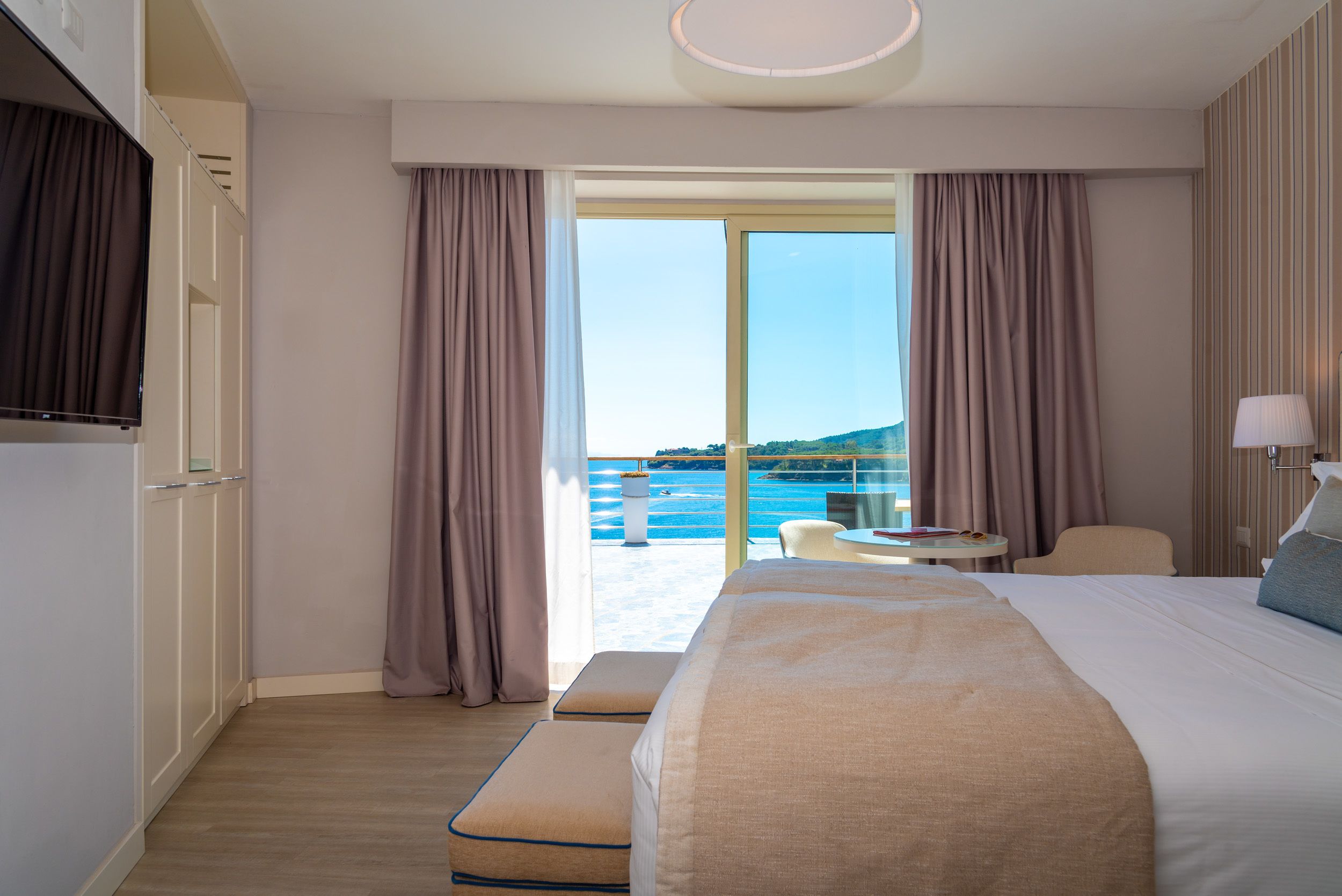 Une chambre d’hôtel avec un grand lit, un bureau, une chaise et une vue sur la mer.