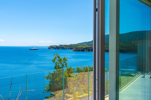 A balcony with a clear view of the sea and a distant island. - Hotel Plaza (Porto Azzurro)