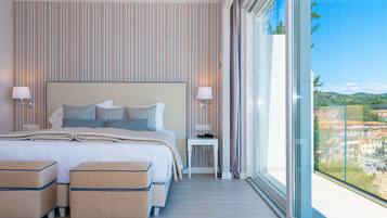 A modern hotel room with a large bed, two bedside tables, a small side table, and a large window offering a city view.