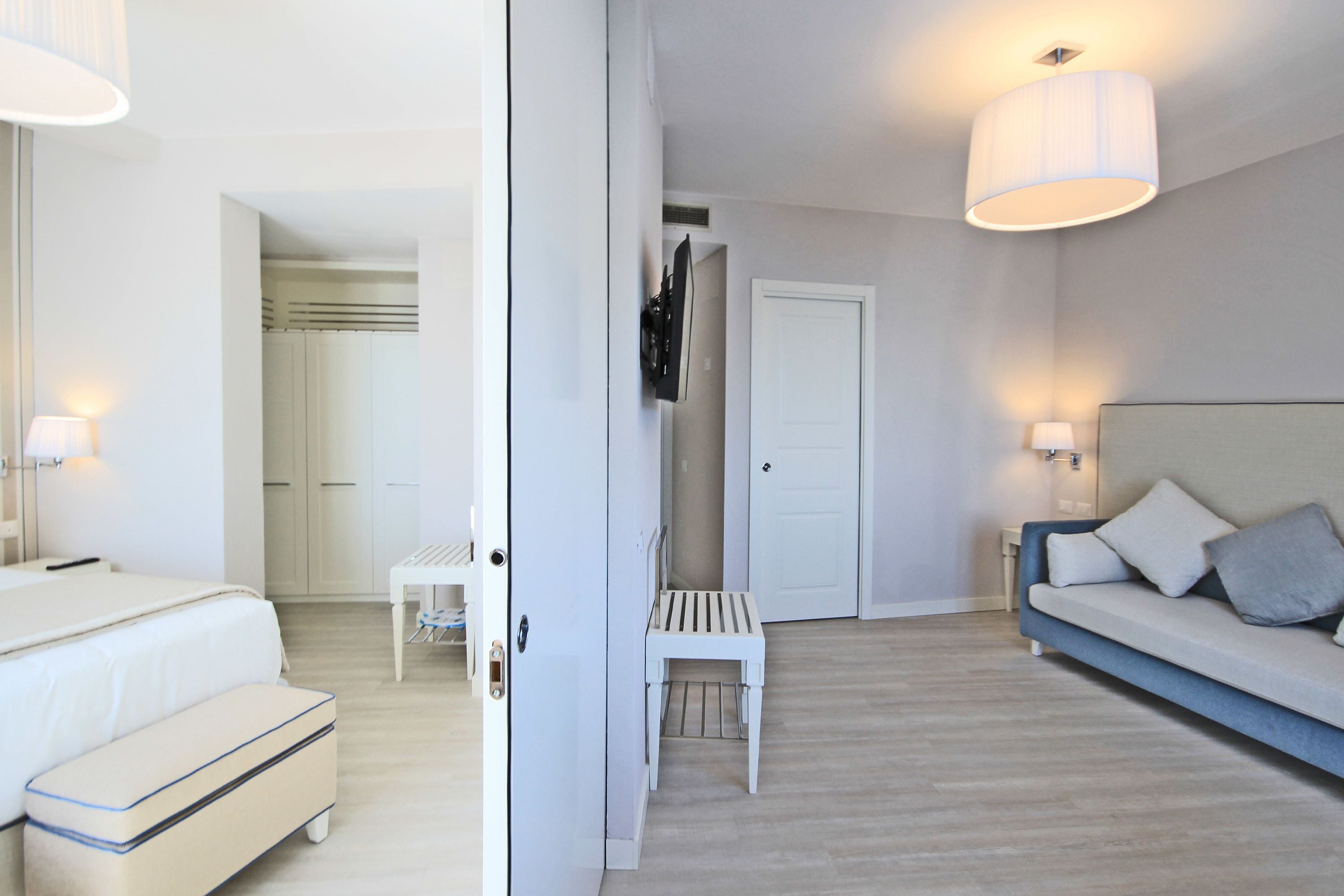 A modern bedroom with a bed, a sofa, a small table, and a bench.
