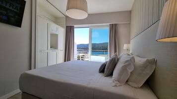 Une chambre à coucher avec un grand lit, une armoire, une fenêtre donnant sur la mer et un lampadaire au plafond.