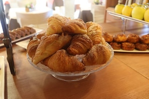 A glass bowl filled with croissants on a wooden table. - Maison Cly Hotel & Restaurant (Chamois)