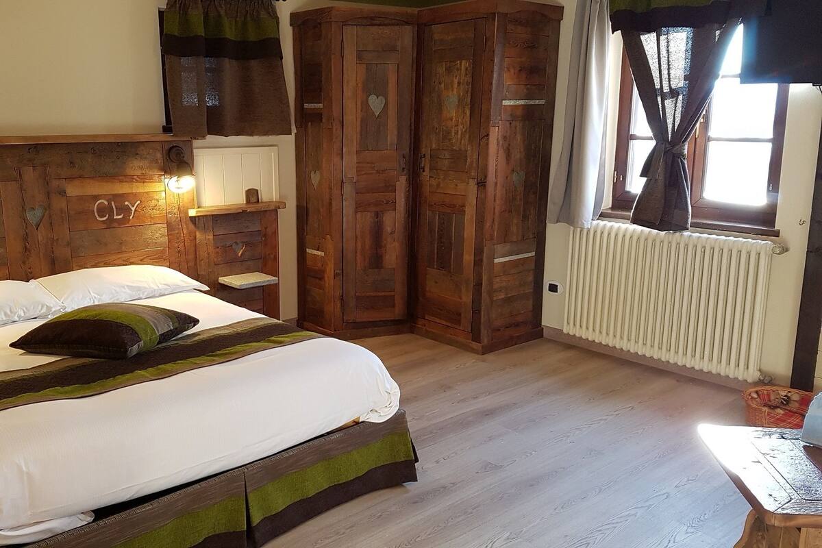 A cozy bedroom with a wooden headboard, a bed with white bedding, and a window with curtains.