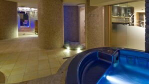 Un área de spa con hidromasaje, paredes de azulejos y una zona de estar con una silla.