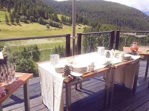 A wooden deck with a table set for a meal, overlooking a mountainous landscape. - Maison Cly Hotel & Restaurant (Chamois)