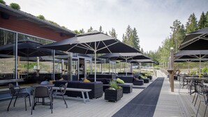 An outdoor patio area with seating, umbrellas, and a wooden deck. - Bergshotellet (Jarvso)