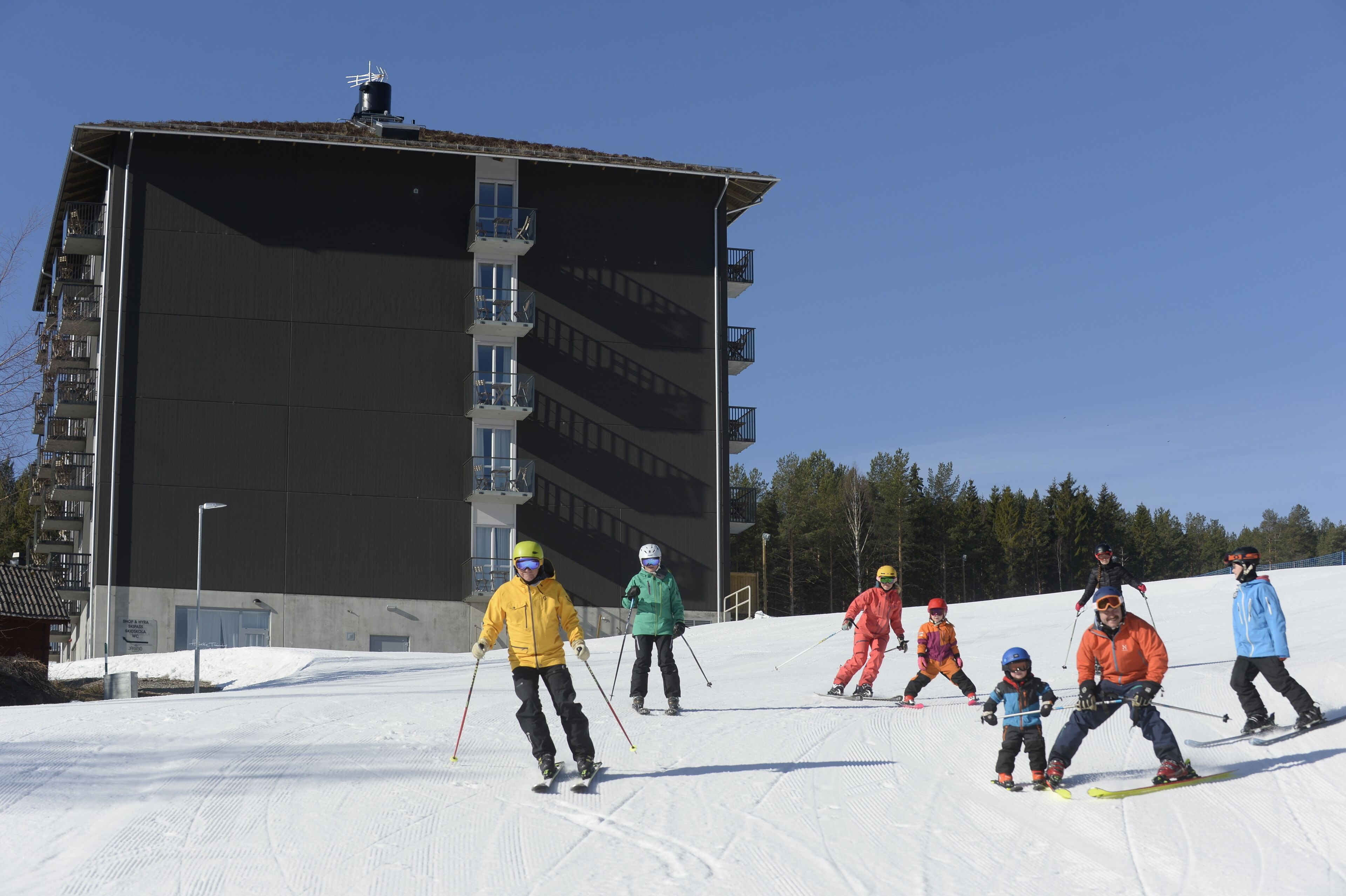 Eine Skipiste mit Skifahrern und einem großen Gebäude im Hintergrund.