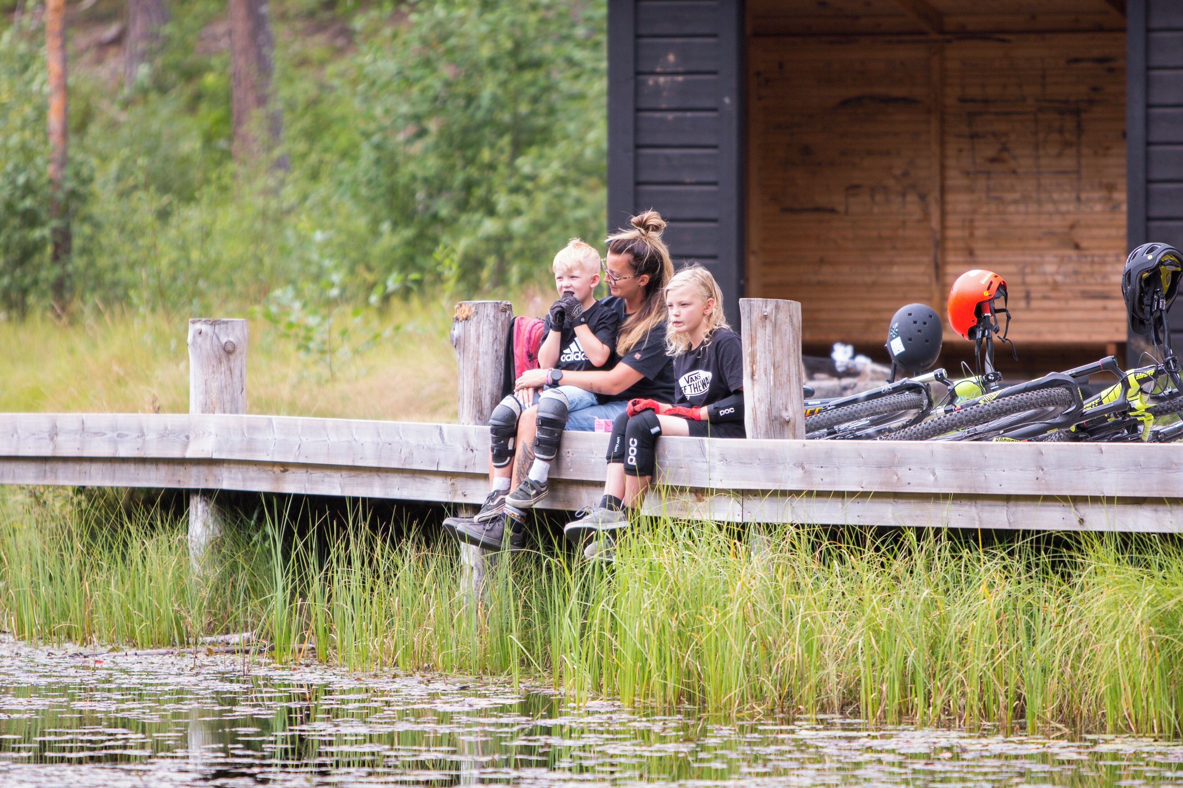 A wooden dock over water with people sitting on it.