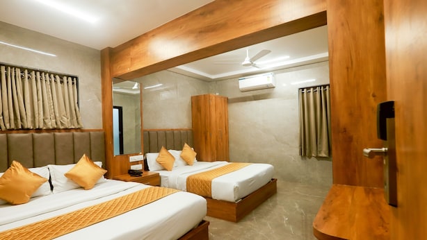 Habitación de hotel con dos camas, cabeceros de madera, un espejo grande y un ventilador de techo.
