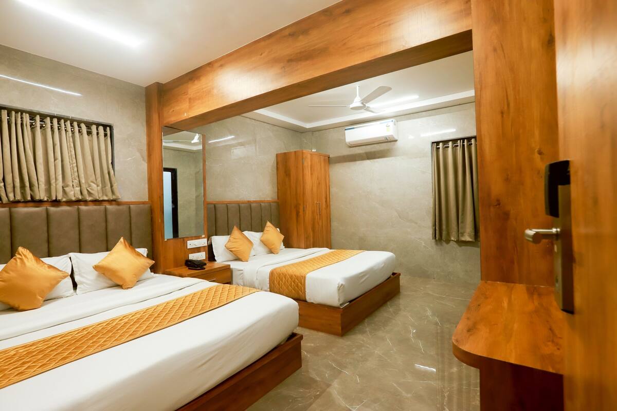 Ein Hotelzimmer mit zwei Betten, Holz-Kopfteilen, einem großen Spiegel und einem Deckenventilator.