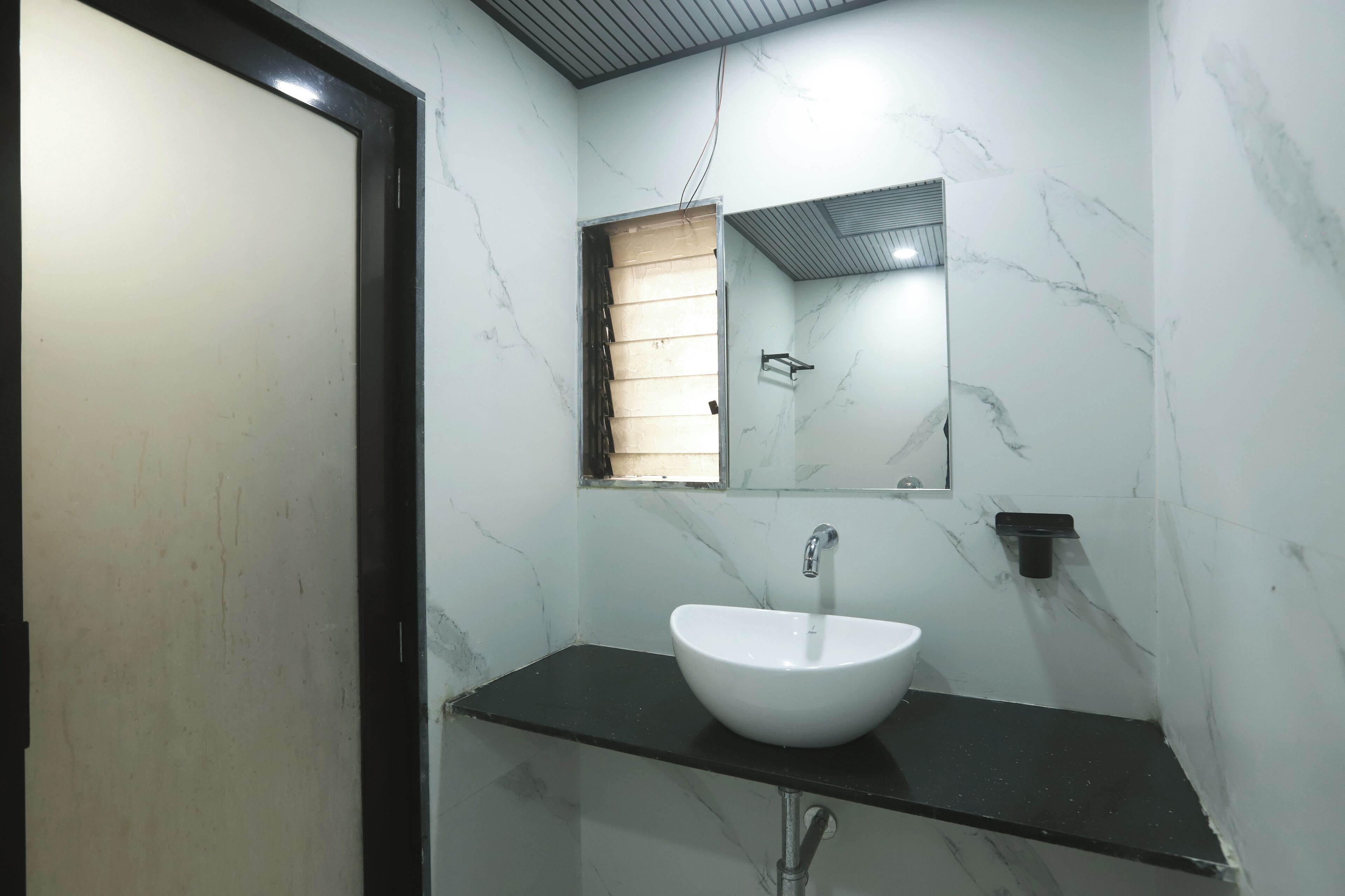 A bathroom with a white sink, black countertop, and a mirror above it.