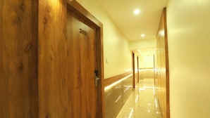 Un pasillo con puertas de madera, cada una con un número. El suelo es brillante y reflectante.
