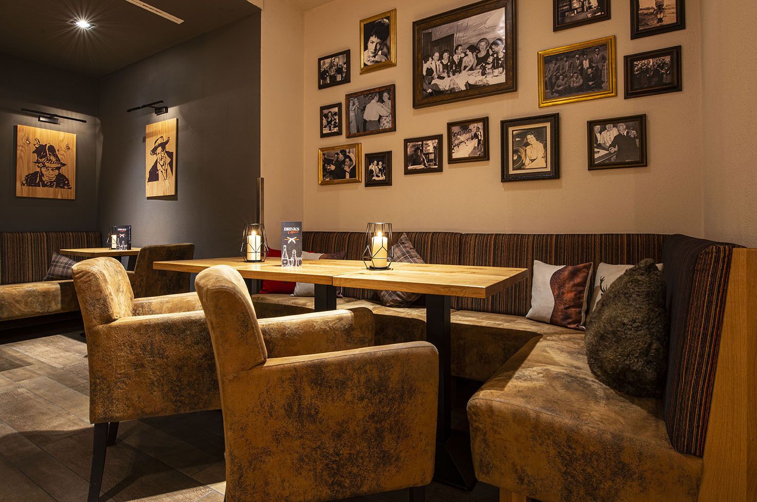 Un restaurante con mesas de madera y cabinas acolchadas, fotografías blanco y negro enmarcadas en la pared y un atril para el menú.