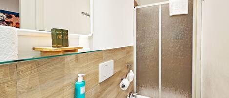 A bathroom with a glass shower enclosure, a white sink, and a mirror above the sink.