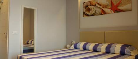 Un dormitorio con cama, puerta y una obra de arte colgada en la pared.