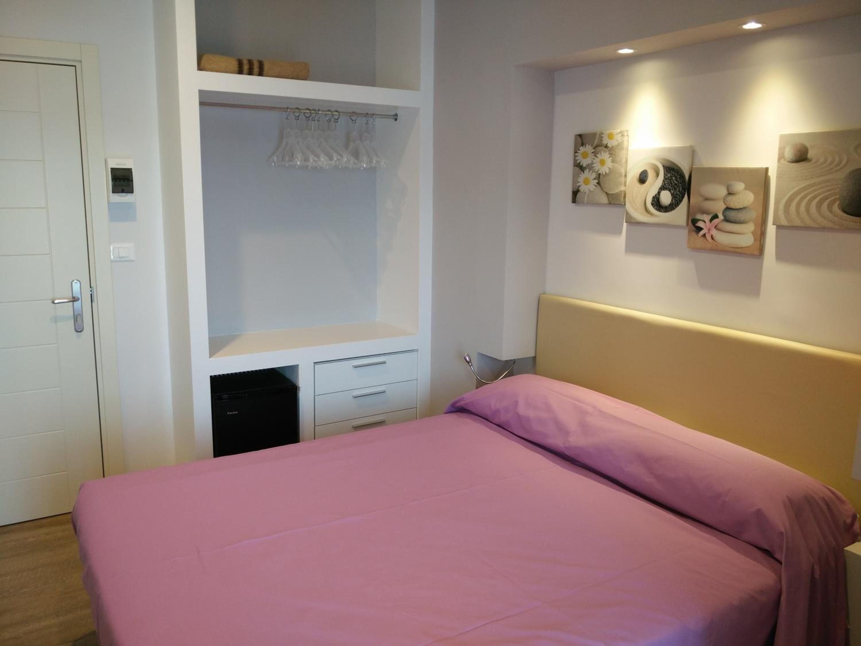 A bedroom with a bed, a built-in wardrobe, a bedside table, and wall art.