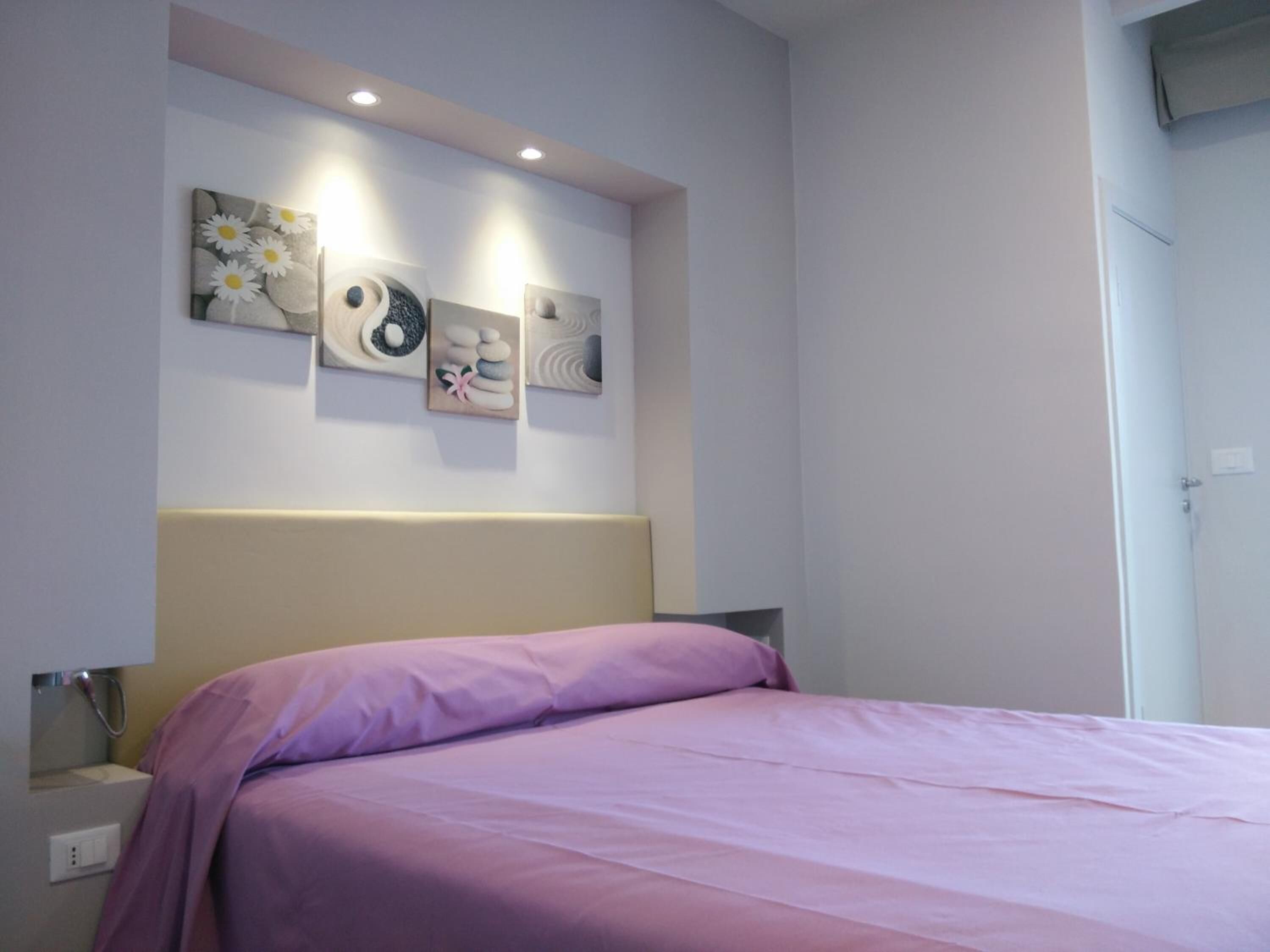Un dormitorio con cama, cabecera y decoración en la pared.