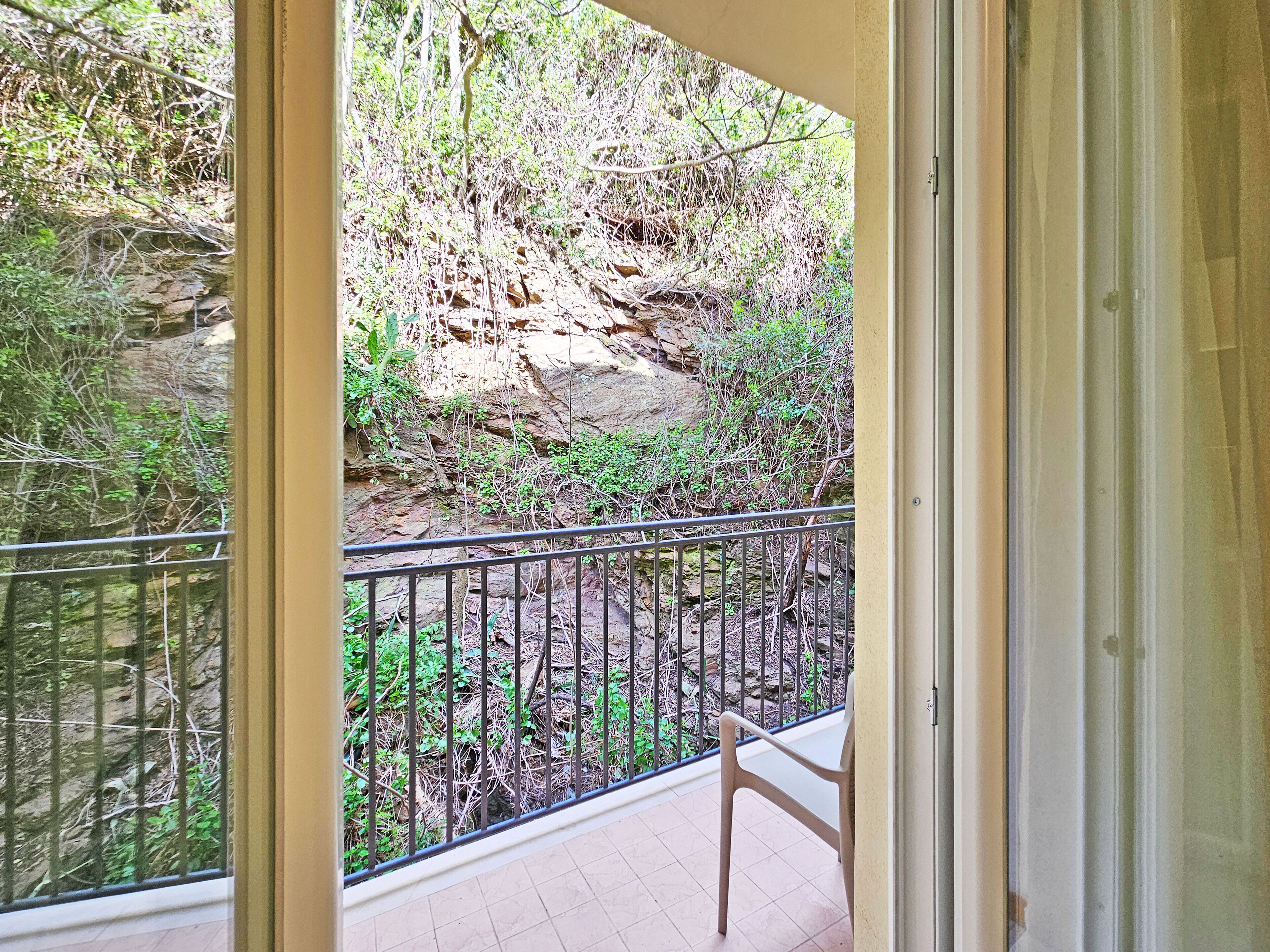 A balcony with a view of a rocky cliff and dense vegetation.