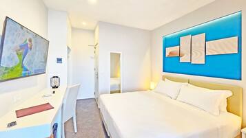 Habitación de hotel con cama, escritorio, silla y televisor montado en la pared.