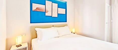 Una habitación de hotel con una cama grande, dos mesitas de noche y una pared decorada en azul.
