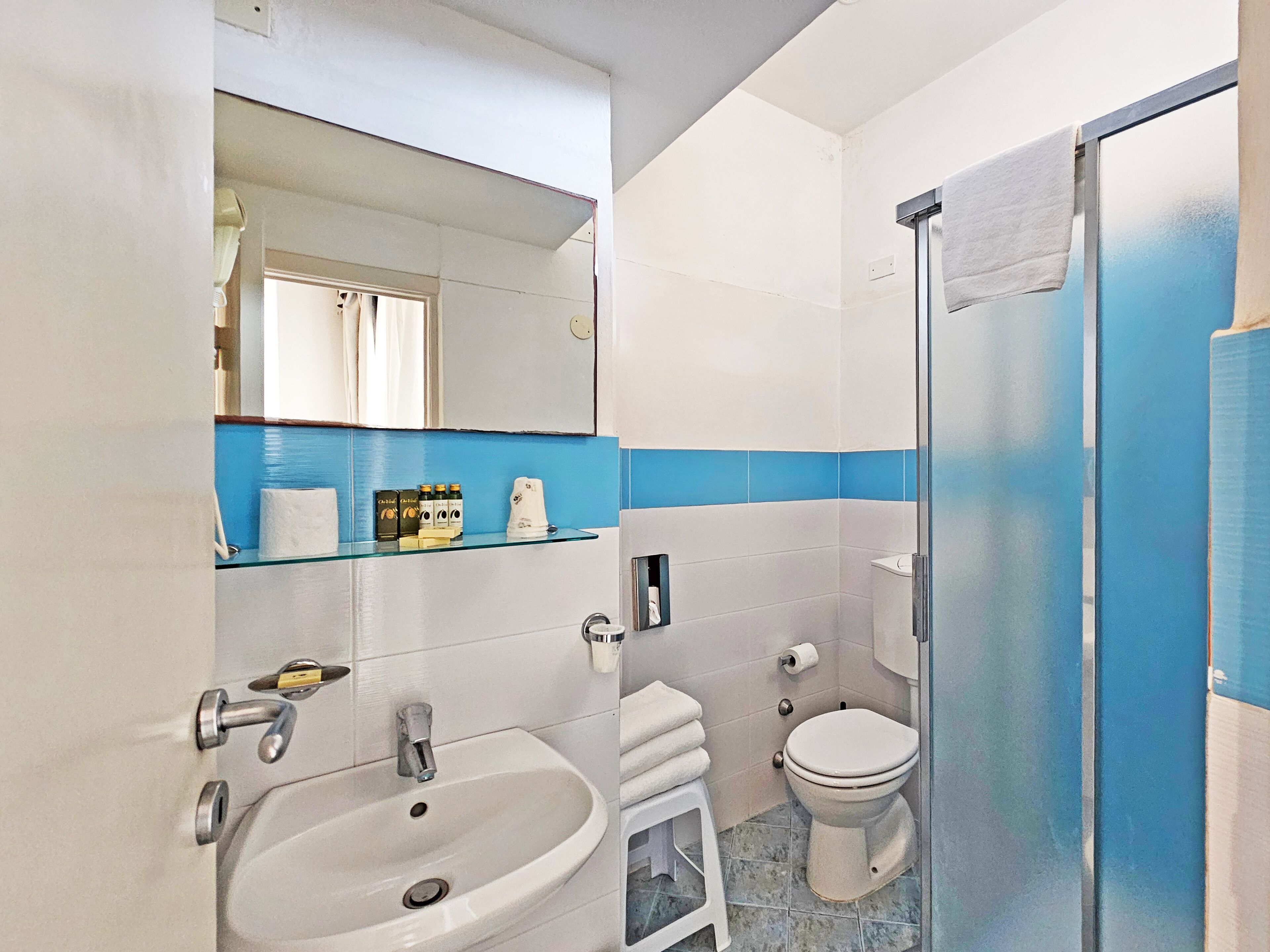 Une salle de bain avec un lavabo blanc, des toilettes et une douche à parois de verre.