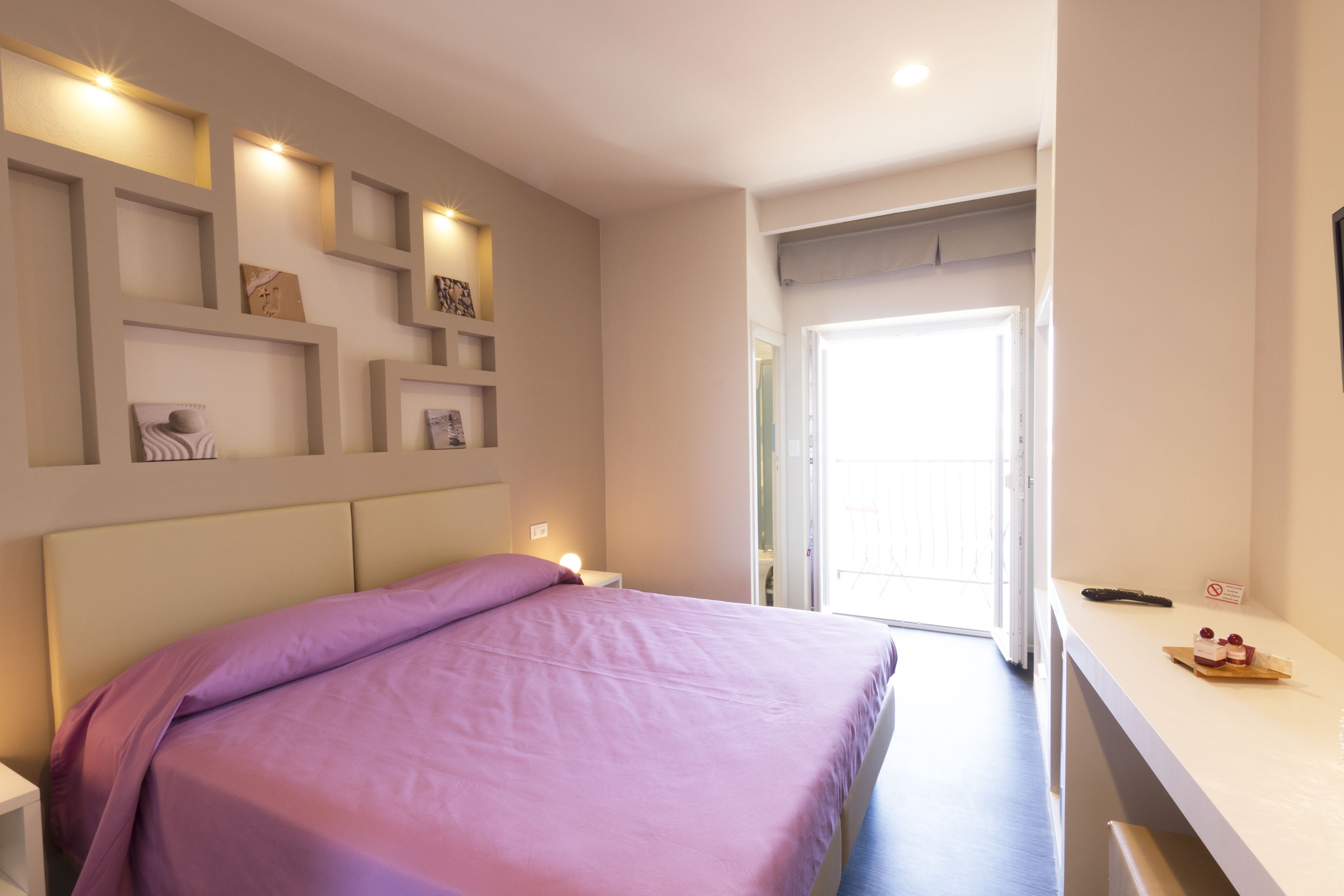 A bedroom with a bed, bedside tables, and wall-mounted shelves.